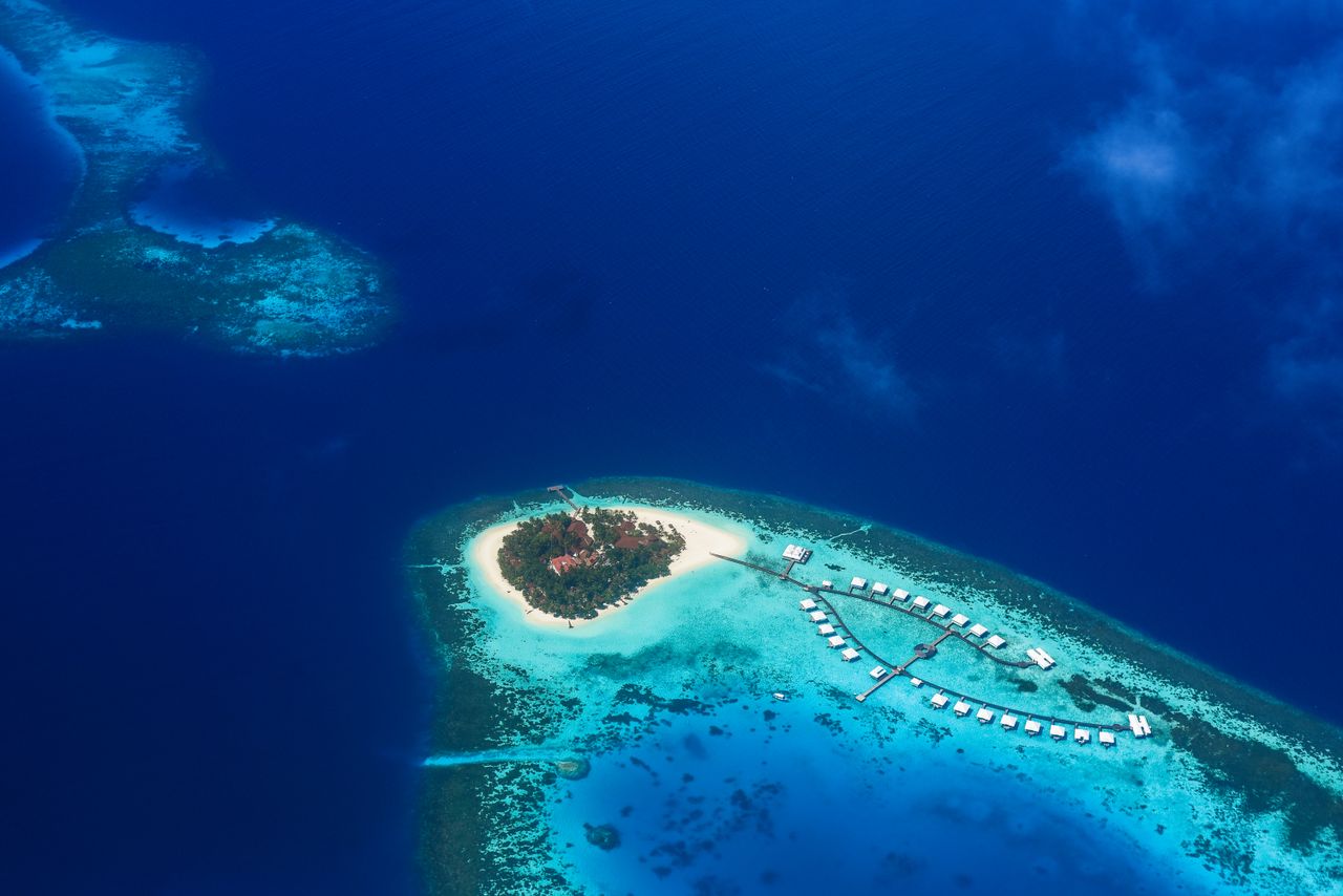 Aerial perspective of a lush tropical island surrounded by turquoise water