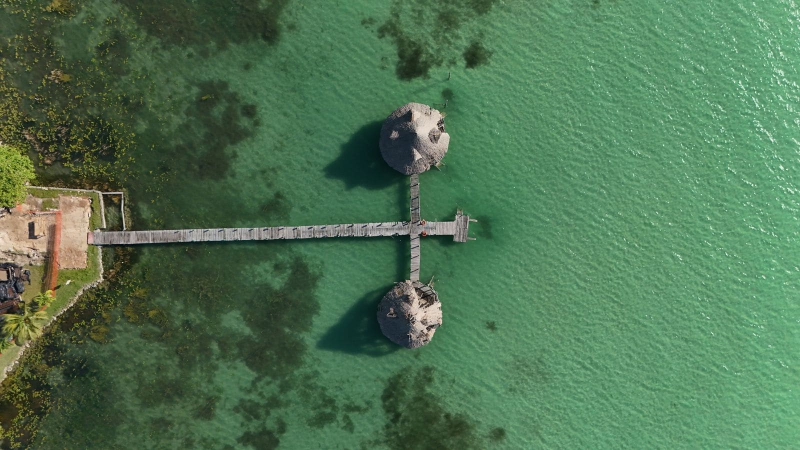 A wooden dock extending into clear turquoise water on a tropical island