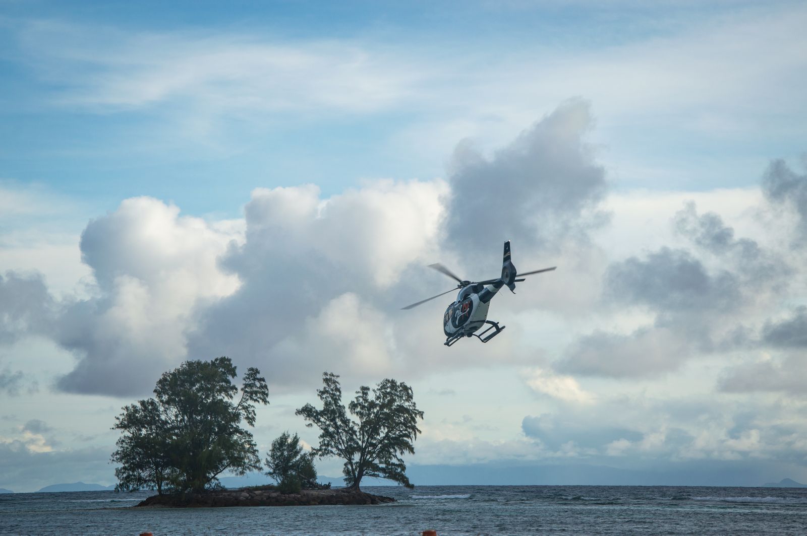 A concrete helipad on a grassy clearing with ocean in the background