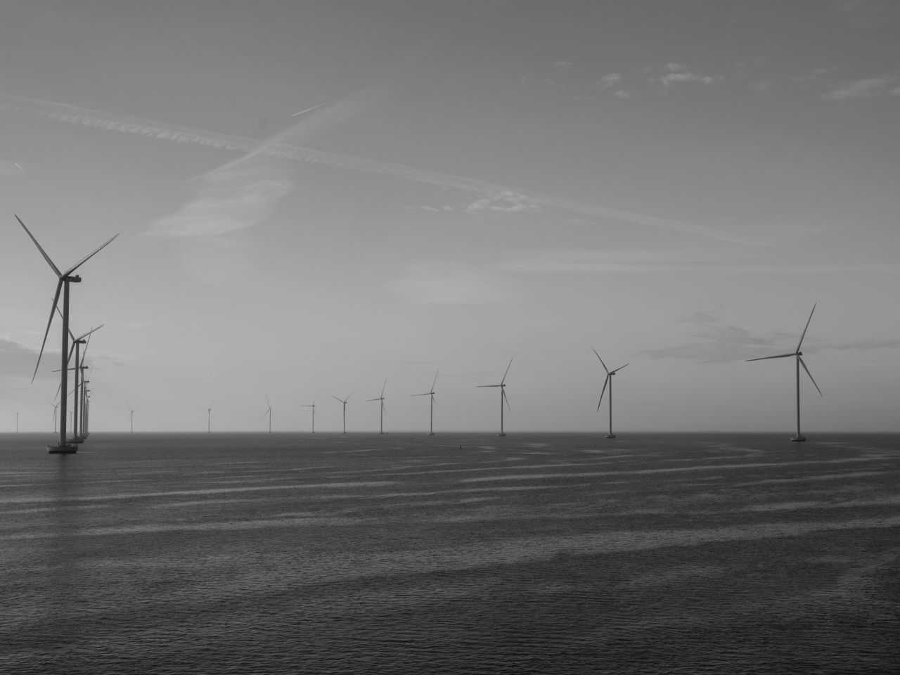 Series of offshore wind turbines anchored on the seabed beyond an island