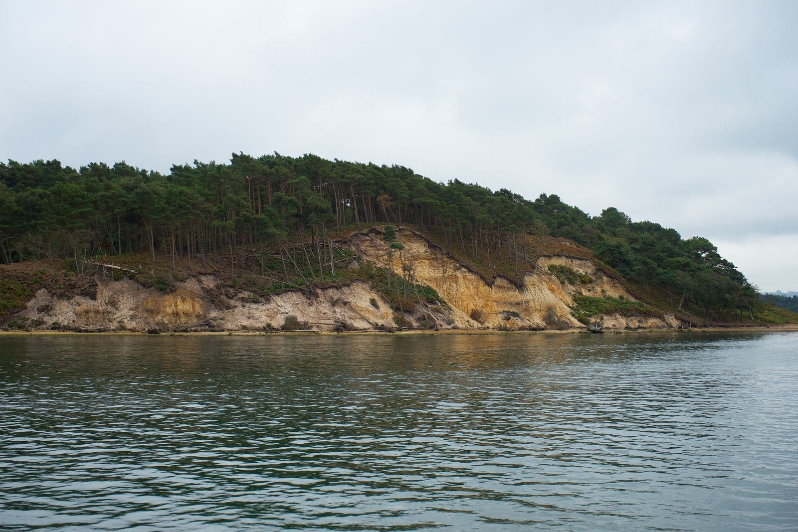 Steep forested cliffs dropping to a blue lagoon on a remote island