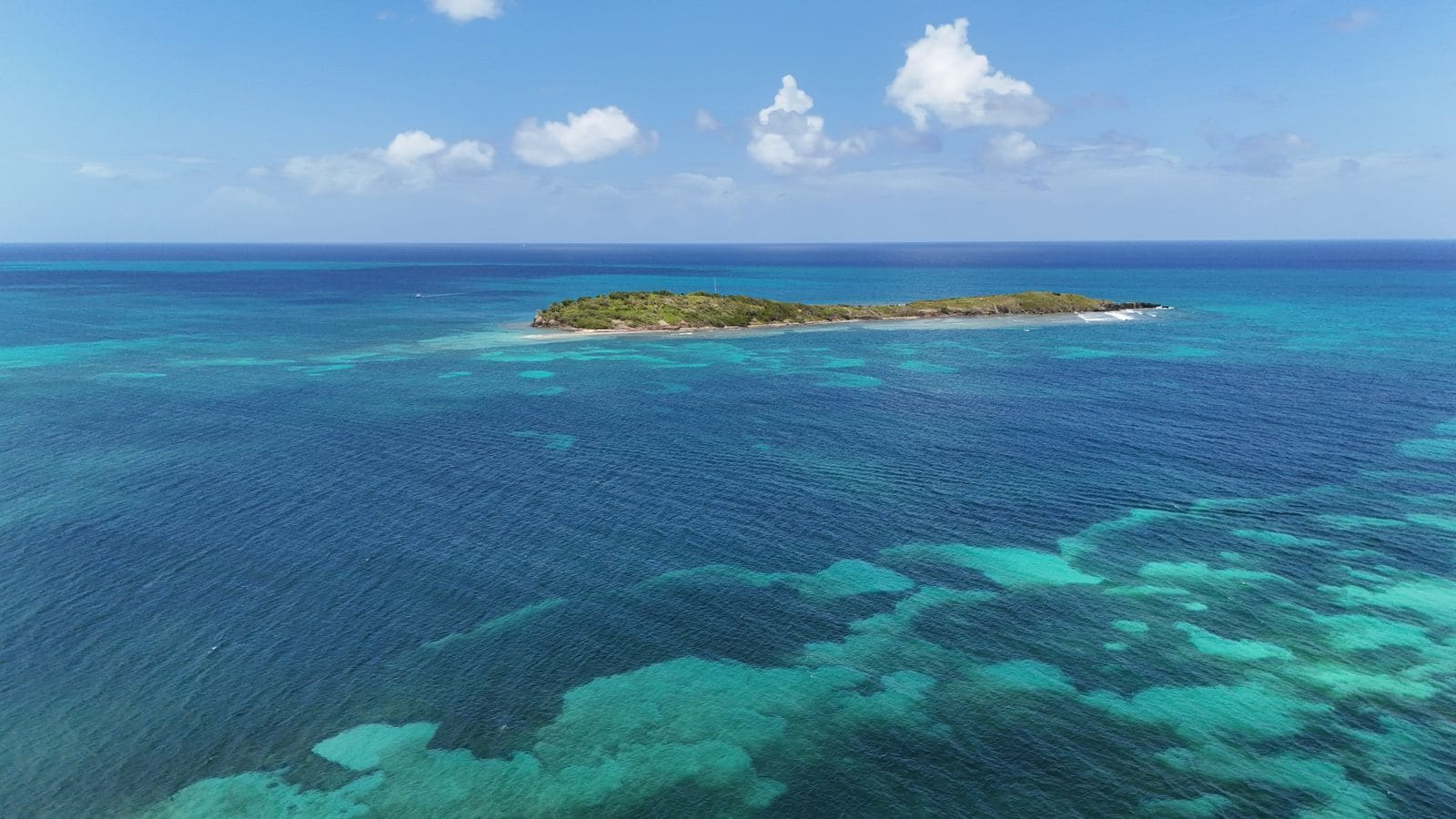 Aerial view of a lush tropical island surrounded by turquoise water
